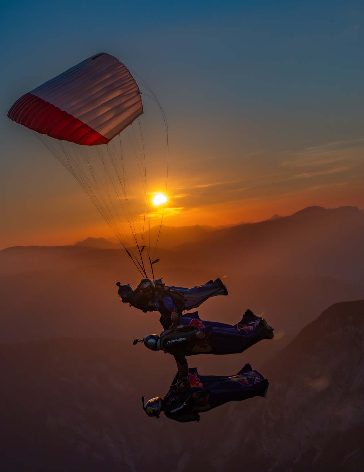 XRW formation with wingsuit pilots and a canopy above the mountains at sunset